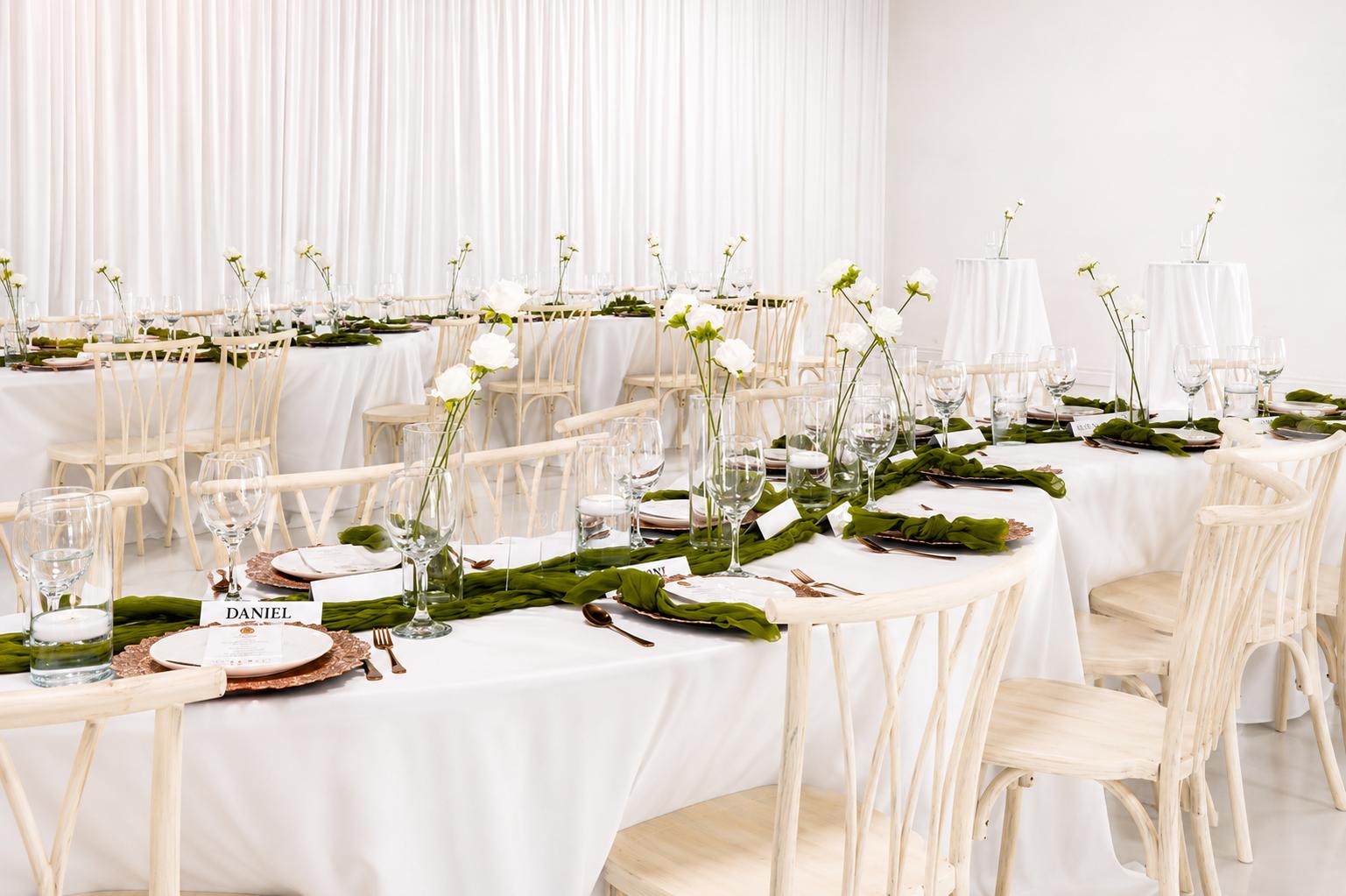 Elegant white tablescape with greenery runners and crossback chairs
